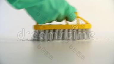 工人用黄色刷子和绿色防护手<strong>套用</strong>洗涤剂清洗地板